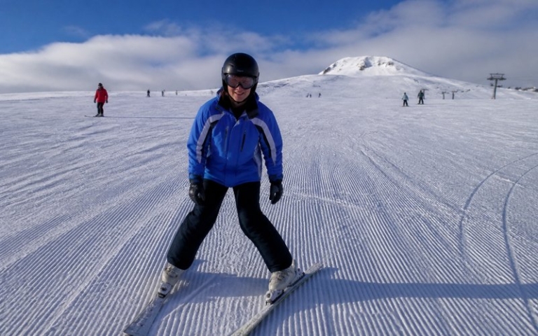 Anfänger auf breiten Skiern auf blauer Piste