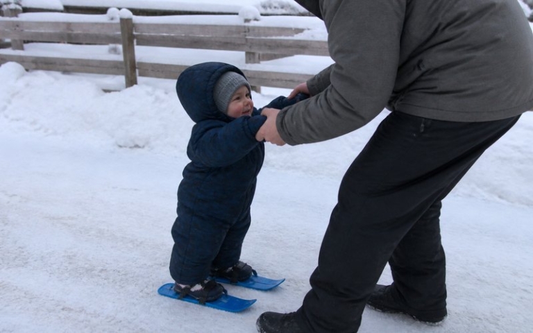 Kleinkind mit Miniski im Schnee