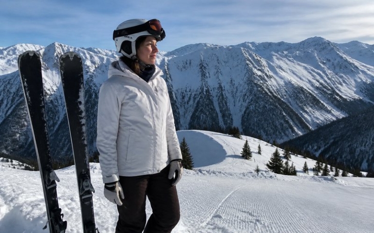 Skifahrerin am Pistenrand mit ihren Skiern