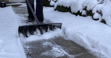 Schneeschieber räumt den Gehweg frei